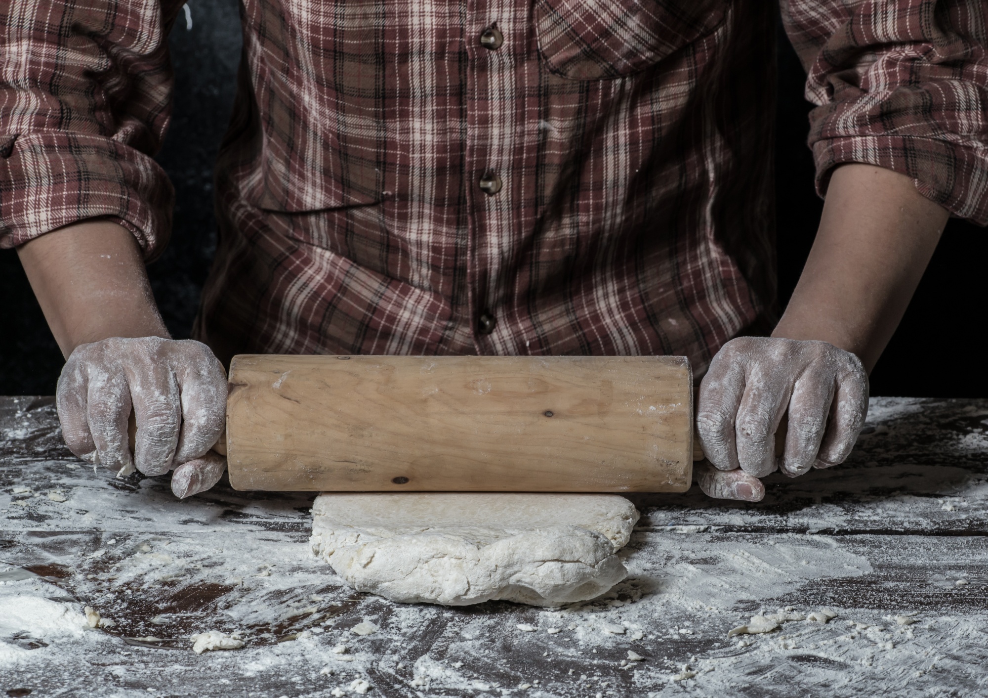 Hands kneading dough on wooden board