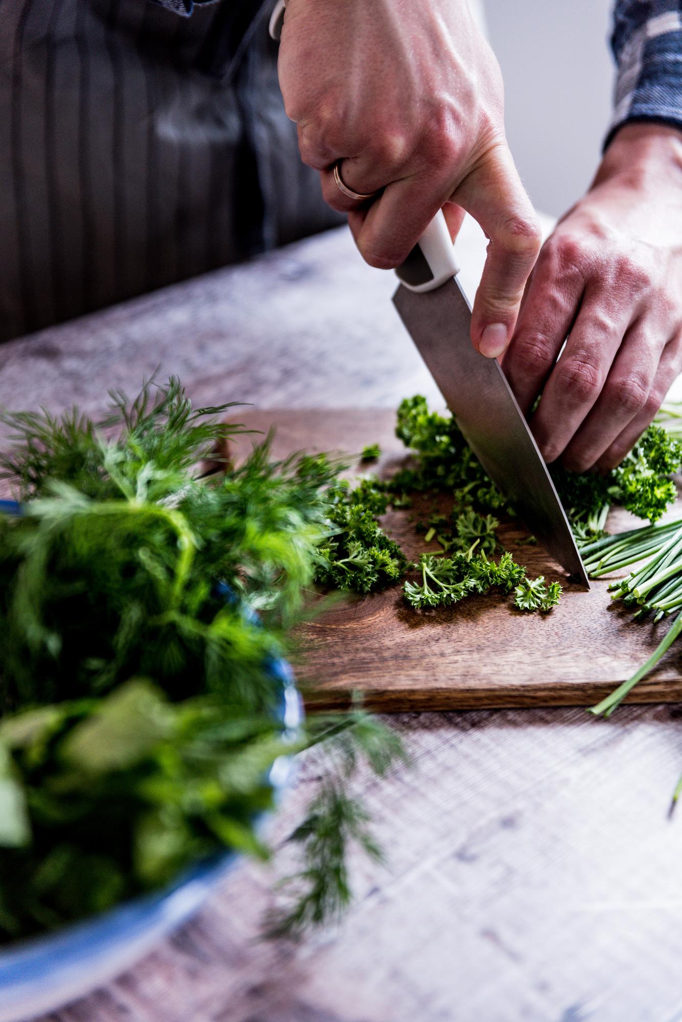 Chef slicing herbs on counter